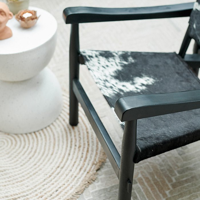 The Tilbury Hide Chair, a mid-century style accent chair featuring cowhide print and a sleek black wooden frame.