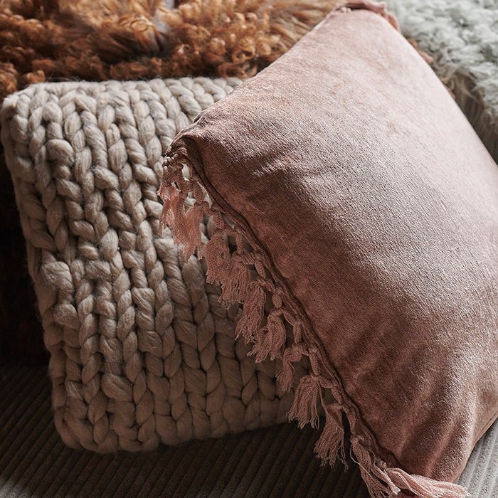 The Uvero Cushion next to a smaller square cushion in a blush colour with a soft chunky knit woven texture.