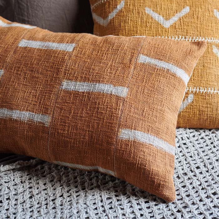 Detail of the texture on a rectangular cushion with a terracotta and cream cover with a simple brick design.