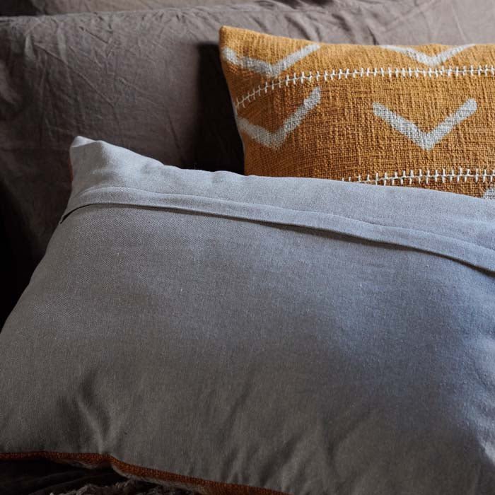 Detail of the covered zip opening and plain cover on the back of a rectangular cushion.
