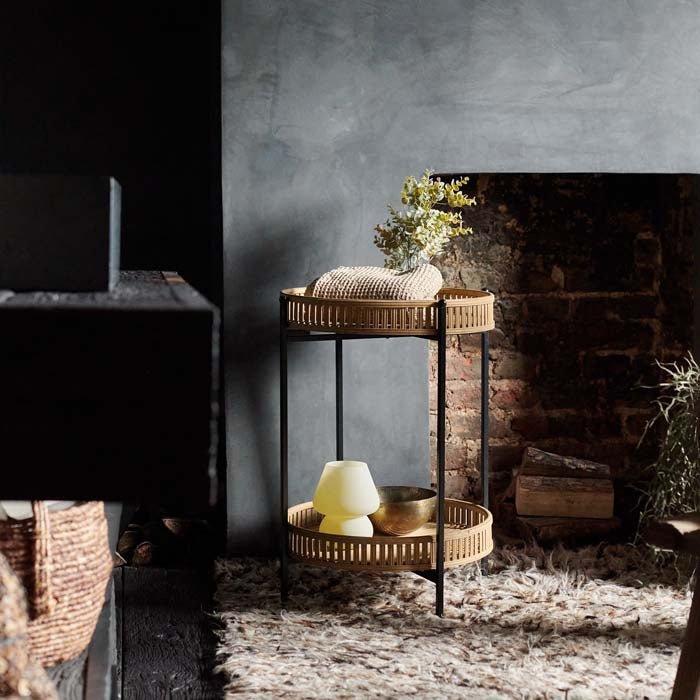 The Casoni Bamboo Side Table, a 2-tiered bamboo side table with a black frame and a boho vibe, on a shaggy rug.