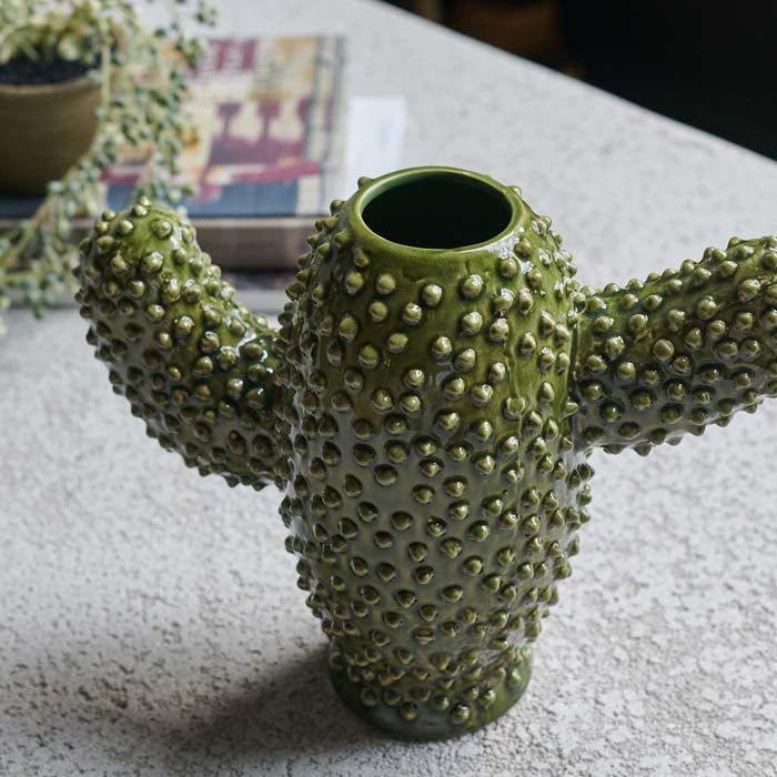 A ceramic cactus vase with a raised textured and a warm green finish.