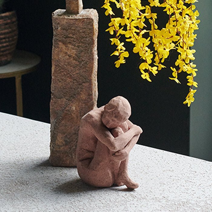 A small curled up figurative sculpture made from brown stoneware.