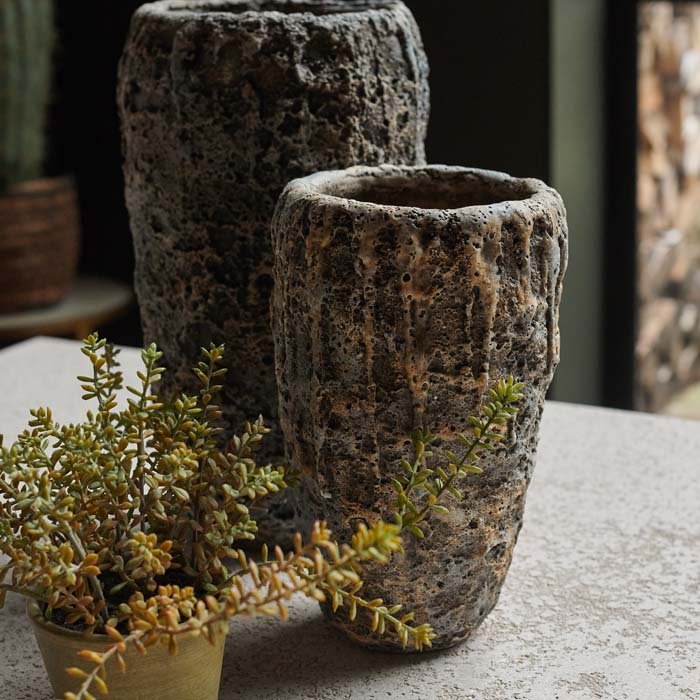 Close image of a medium grey textured vase in front of a larger version and next to a small faux plant.