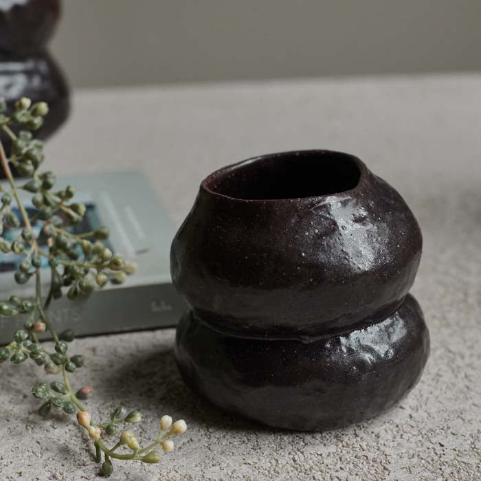 A small curved brown ceramic vase with a smooth glazed finish.