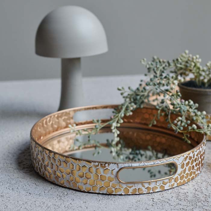 The Vola Mirrored Tray Pair, a set of two mirrored trays with gold and white honeycomb effect sides, next to a white lamp.