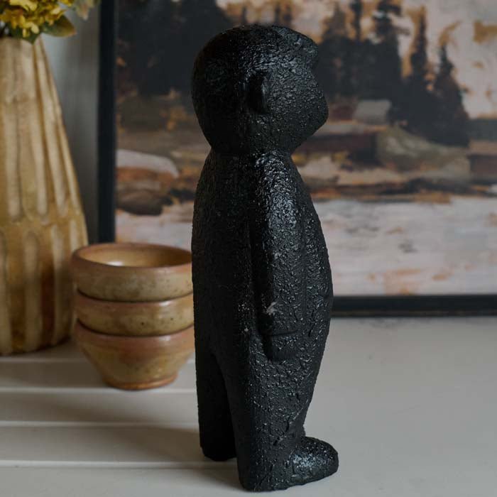 The Amethi Wooden Sculpture, a small figurative sculpture in black wood, next to a set of three glazed bowls.