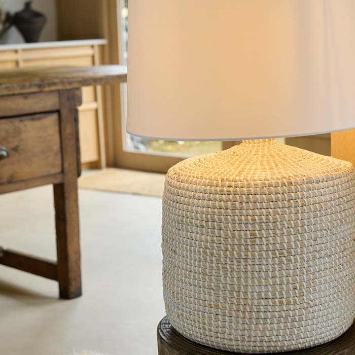 The Devoran Seagrass Lamp, a table lamp with a chunky cylindrical base made from natural seagrass and a white drum shade.