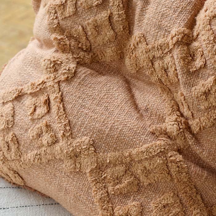 A closeup of the tufted geometric pattern on the soft rust coloured Pamra Cushion.