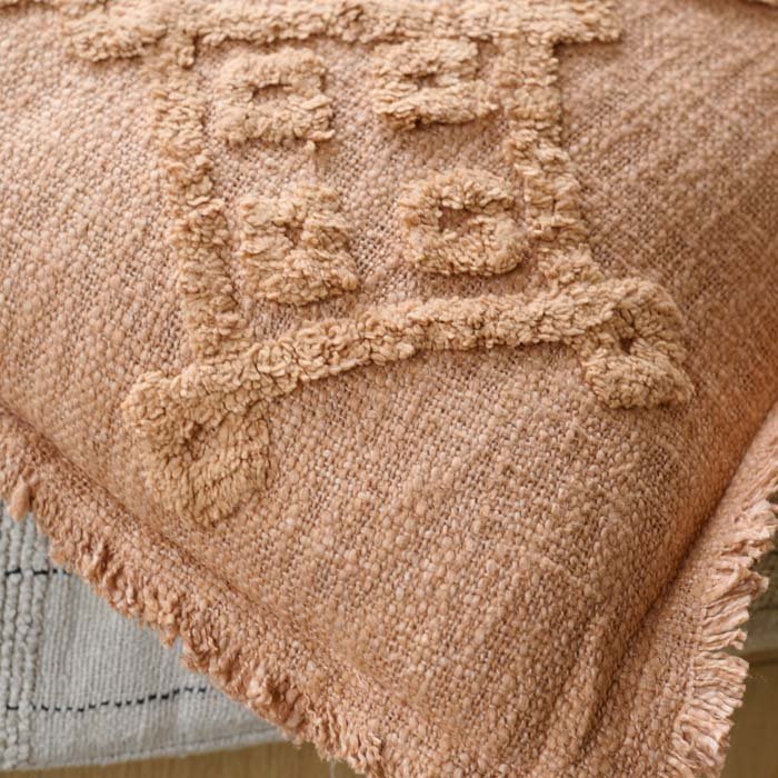 A closeup of the tufted geometric pattern on the soft rust coloured Pamra Cushion.