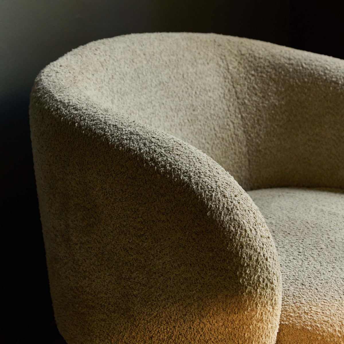 Close-up of a textured beige comfortable chair against a dark interior