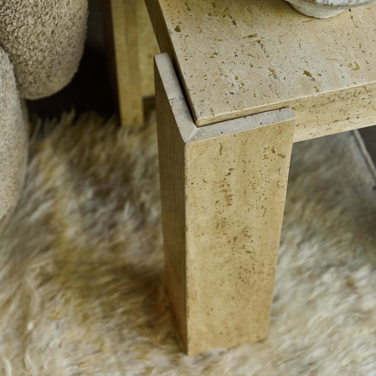 Close-up of the Abigail Ahern Santa Travertine Side Table showcasing its softly textured cream natural stone finish and distinctive sculptural modern silhouette.
