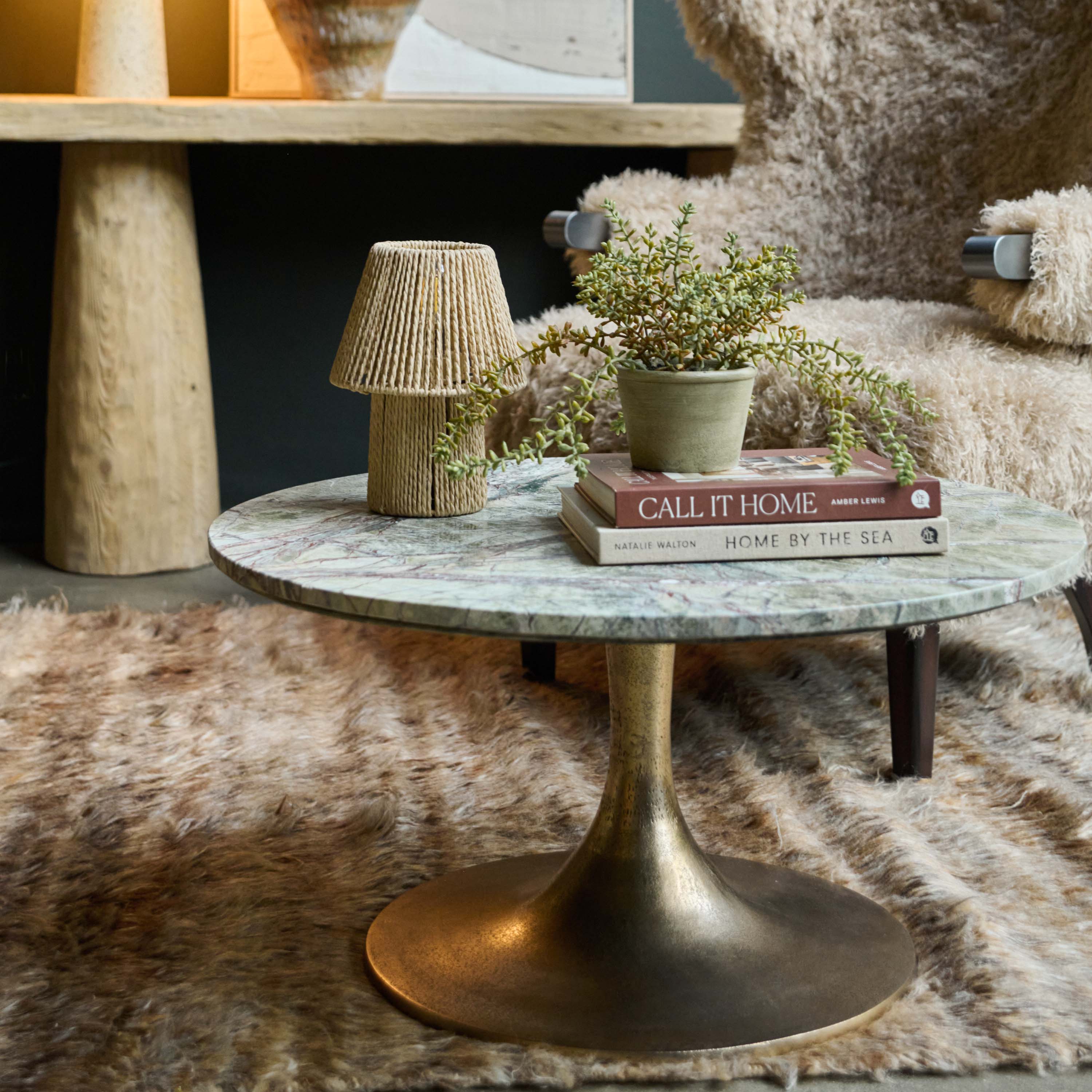 Green marble round coffee table with a natural ssurface, unique veining details and elegant antique gold iron pedestal base. Teller Green Marble Coffee Table by Abigail Ahern, designed as a luxury statement centrepiece for modern living rooms and contemporary interiors. A designer marble coffee table perfect for styling with decorative accessories, books and vases, adding glamour, texture and timeless sophistication to your home decor.