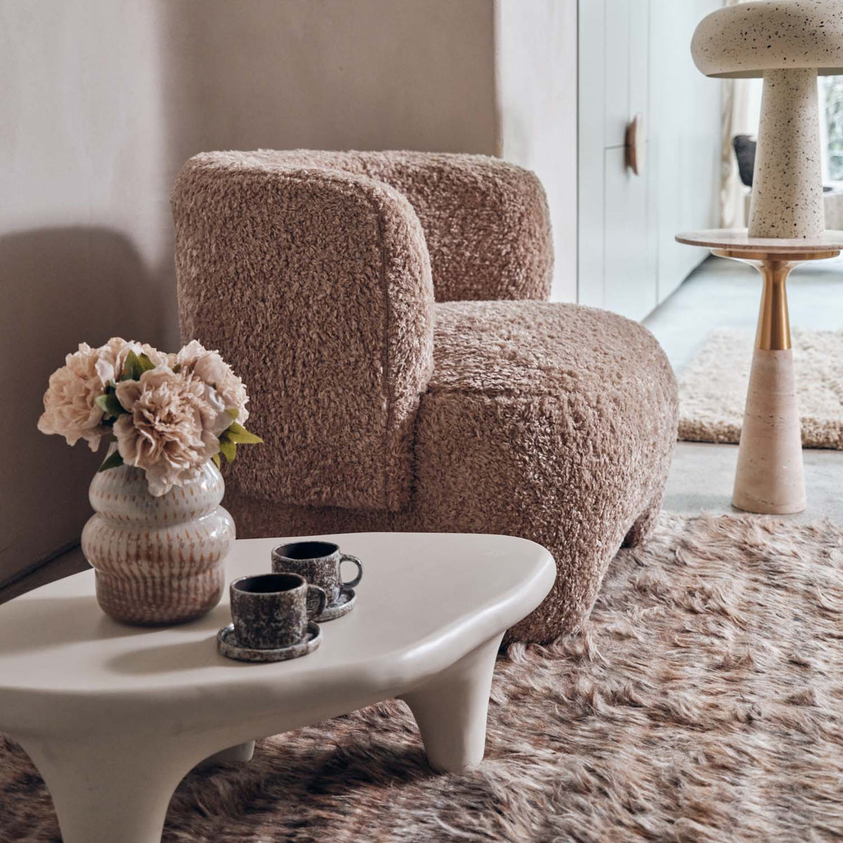 Cream sculptural coffee table in styled living room with accent chair and layered neutral textures, organic modern furniture for contemporary home interiors

