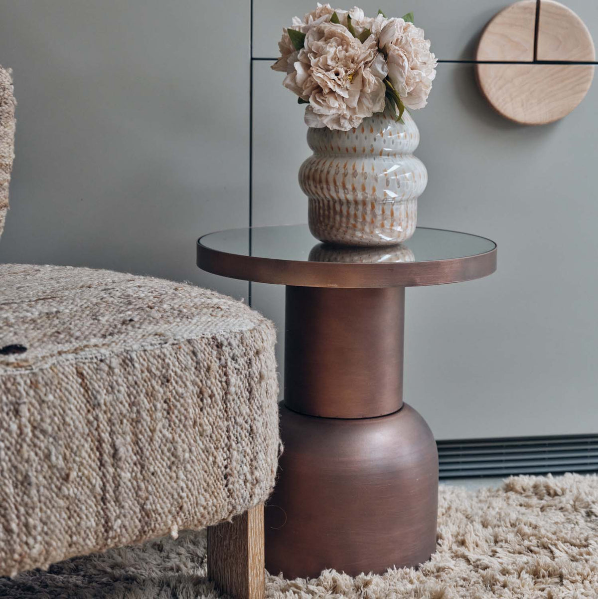 Sculptural bronze iron side table with a mirrored glass top and contemporary curved silhouette for modern luxury interiors.
