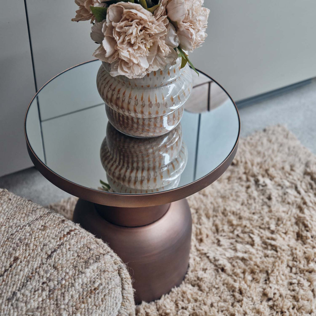 Sculptural bronze iron side table with a mirrored glass top and contemporary curved silhouette for modern luxury interiors.