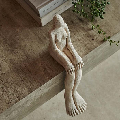 Figurative seated sculpture on the edge of a coffee table.