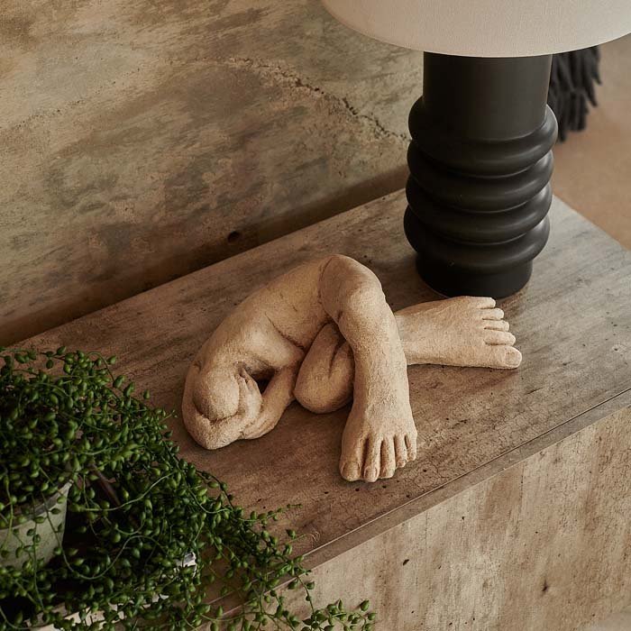 Cement sculpture of a lying figure with enlarged feet.