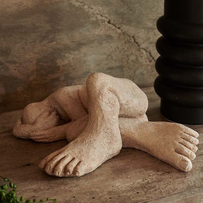 Figurative sculpture of a human form with oversized features. This concrete sculpture is perfect for home decor.