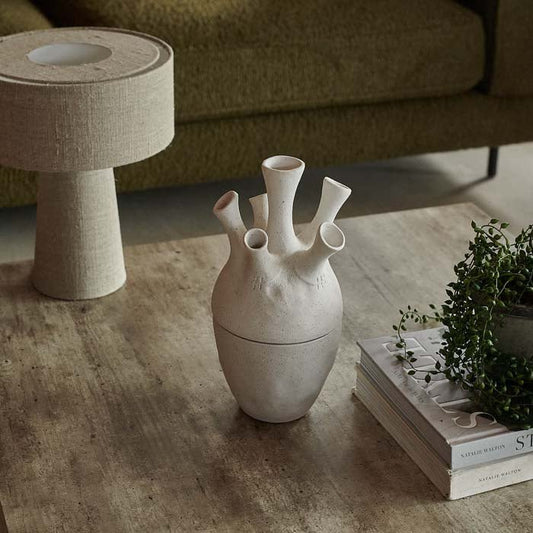 Large white sculptural jar on a wooden coffee table