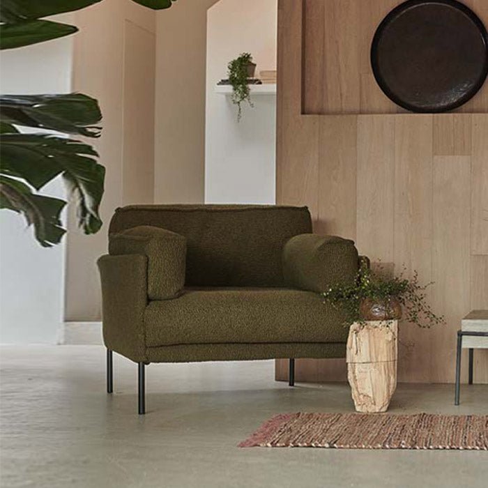 Olive green boucle armchair with a soft textured fabric finish, generous proportions and sleek black iron legs. Eartha Green Boucle Armchair by Abigail Ahern, designed as a contemporary accent chair with a comfortable deep seat and stylish understated silhouette. A luxury statement armchair perfect for living rooms, reading corners and modern interiors, adding rich colour, texture and effortless elegance to your home decor.