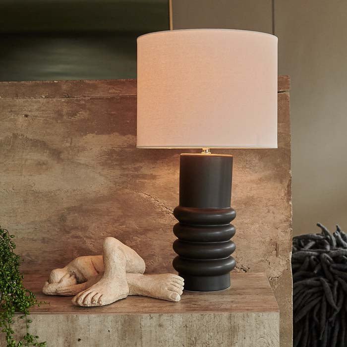 Table lamp with white drum shade and matte black ceramic base.