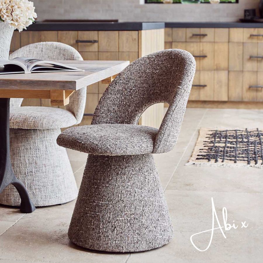 Contemporary upholstered, comfortable dining chair in a textured grey fabric featuring a sculptural curved silhouette a modern but organic design for stylish dining interiors.