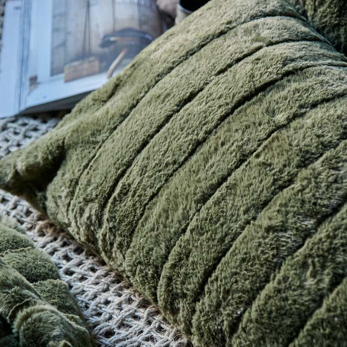 Close up image of the muted green, striped faux fur textile of the Alayna cushion on a rope-like throw.