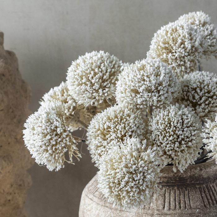 A close up of luxury artificial allium flower stem. White round spiky flowers that add lifelike texture to vases. Realistic spherical faux flower stem to add a natural look to flower bouquets. Luxury artificial flowers that look lifelike from Abigail Ahern known for boundary pushing designs. White allium flowers that look like they have been hand picked from the garden.