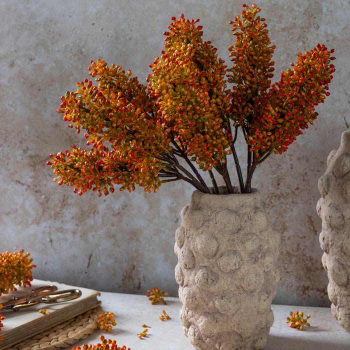 A bouquet of vibrant artificial orange flower buds arranged in a bobble textured vase.