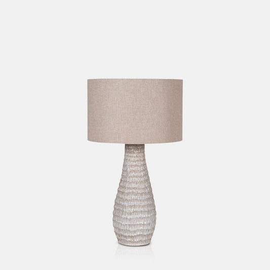 Textured cream base and round shade of a tall table lamp