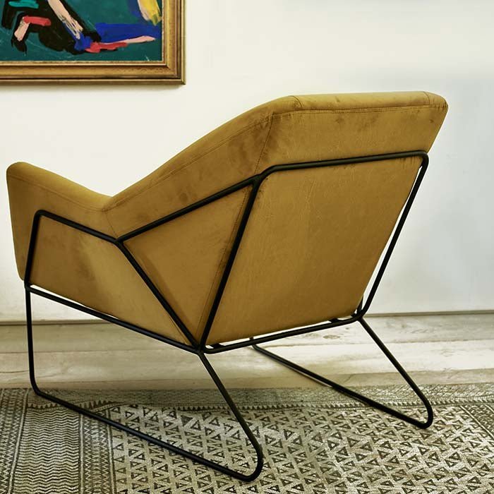 The Atura Occasional Chair, a large angular yellow velvet armchair with a black metal frame and metal legs.