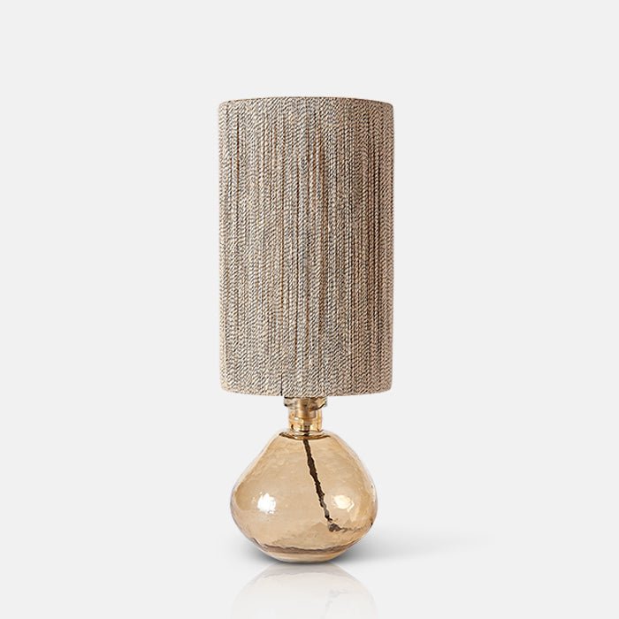 Table lamp with organic amber glass base and tall rattan shade.