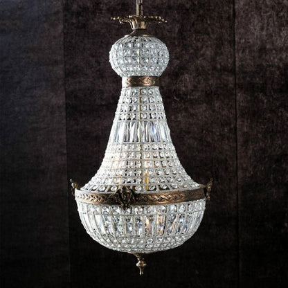A regal chandelier with clear glass beads and engraved bronzed metal detailing.