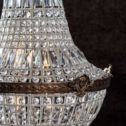 Clear glass beads in circular and rectangular shapes, with engraved bronze detailing, on a chandelier.