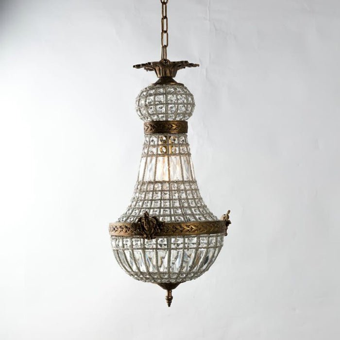 A bronze metal and clear glass beaded chandelier hanging by a metal chain.