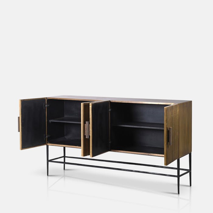 Four cupboard doors opened on a gold sideboard revealing black shelves Abigail Ahern Banbury Sideboard in antique brass with a warm metallic gold finish, streamlined rectangular shape and generous enclosed storage.