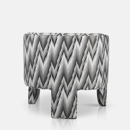 Curved back of a three legged armchair in a grey zig zag fabric