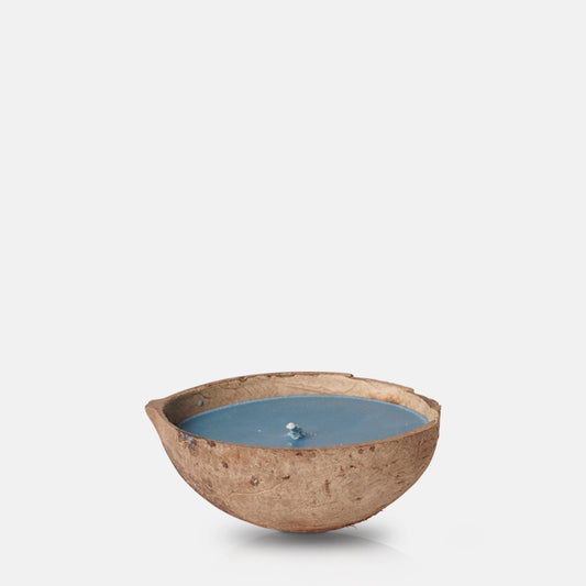 Blue coloured scented candle placed in half a coconut shell 