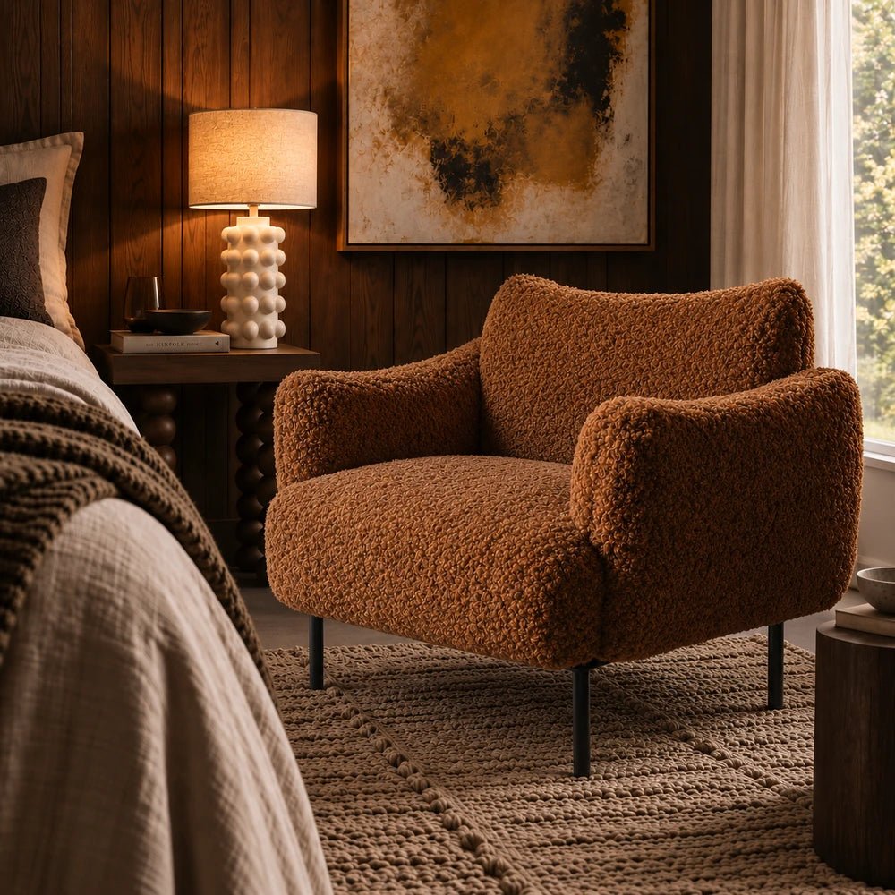 Belville Armchair in toffee brown upholstery with rounded cushioned form, styled in a warm contemporary living room with layered neutral textures.