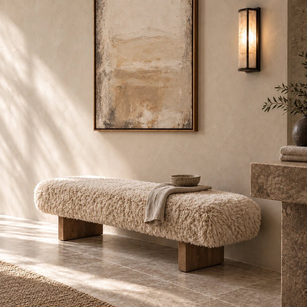 Bertrand Faux Fur Bench with soft cream textured upholstery and rounded form, styled in a warm neutral living room with layered contemporary furnishings.