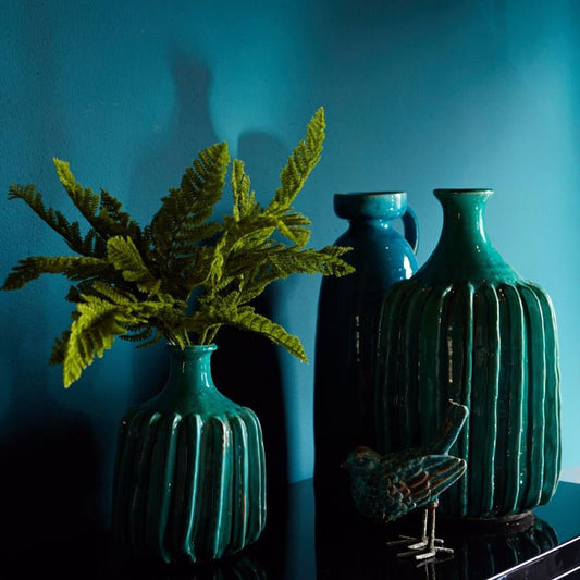 Three blue vases sat in front of a rich blue painted wall