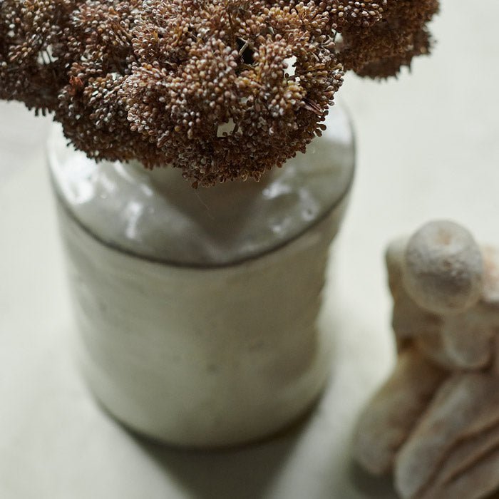 The Bremen Vase - Large, a glossy white stoneware vase with a chunky cylindrical base and a rustic feel, with faux florals.