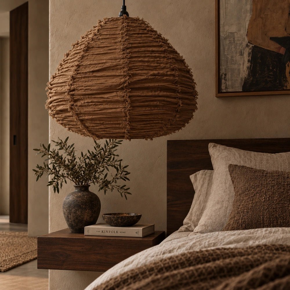 Brenta Fabric Pendant Light with gathered neutral fabric shade shown close beside a bed, creating soft ambient lighting in a warm contemporary bedroom.