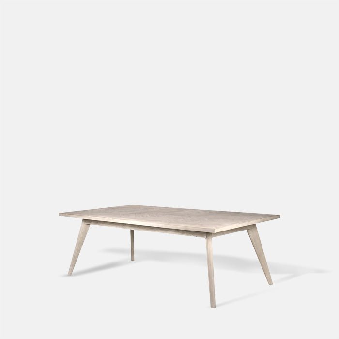A cutout of the Bronson Parquet Dining Table. A rectangular herringbone wooden tiled patterned dining table.