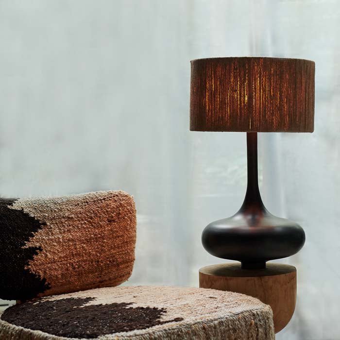Brooklyn Table Lamp, a sculptural black curvy table lamp with a jute shade styled on a side table next to a textural chair.