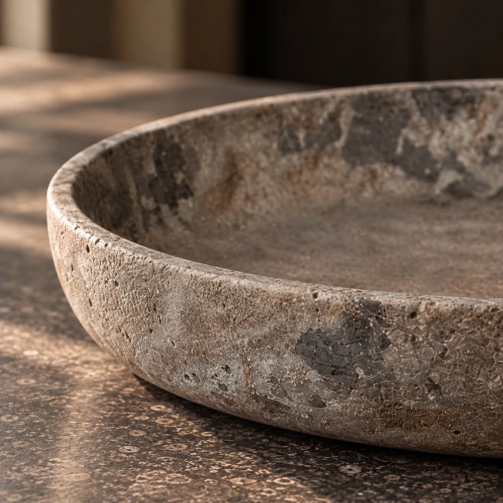 Broxtowe Cement Bowl shown in close-up, highlighting its shallow rounded shape, mottled textured surface and irregular stone-like finish on a dark kitchen counter.