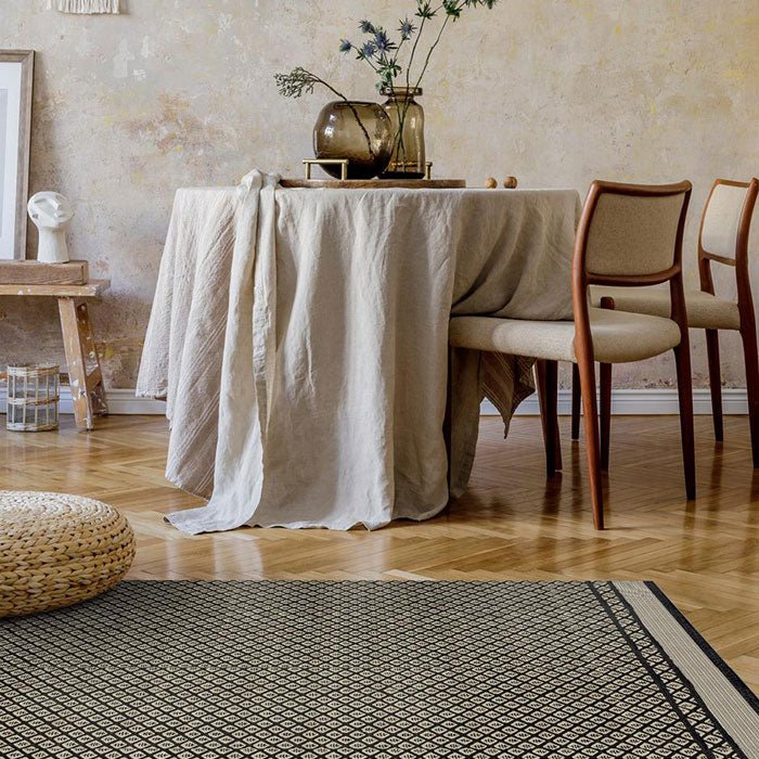 Black and beige diamond patterned vinyl rug displayed on a wooden parquet floor.