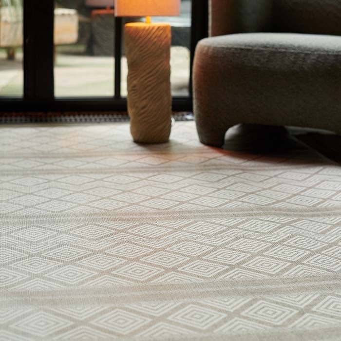 Canta Vinyl Flooring, a diamond and striped pattern vinyl rug styled in a living room under a floor lamp and a green chair.