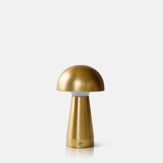 A cutout of gold metal curvaceaous mushroom shaped wireless and portable lamp by Abigail Ahern, known for her rule breaking designs and stylish interiors. Styled on a white background, this small but mighty curvy lamp is super flexible and dimmable too, pop all over the house, style next to your bath, bedside or create intrigue to your tablescapes and a dash of metallic reflection to your kitchen worktops.